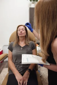 Provider marking a patient's forehead and reviewing an injection record before injectable treatment