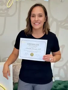 Graduate holding an aesthetic training course completion certificate