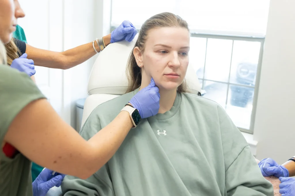Provider performing a facial treatment assessment on a seated patient