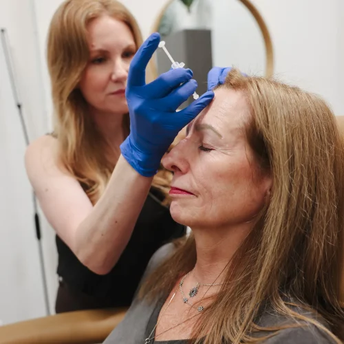 Provider preparing a facial treatment near a patient's brow