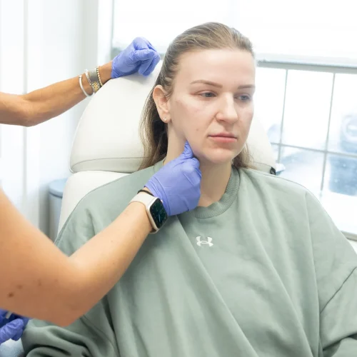 Provider performing a facial treatment assessment on a seated patient